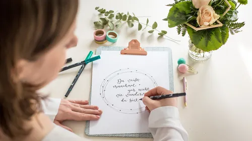 Person schreibt auf Papier mit dekorativem Klebeband.