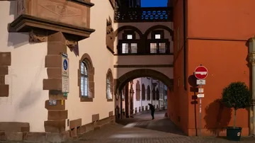 Person walking under archway in historic street.