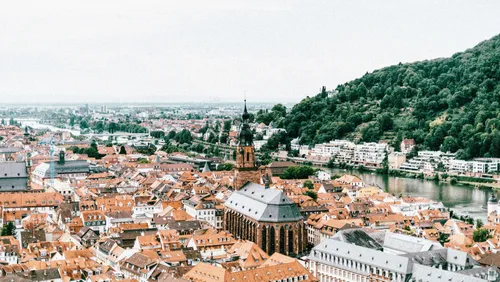 Cityscape with church and river, surrounded by hills.