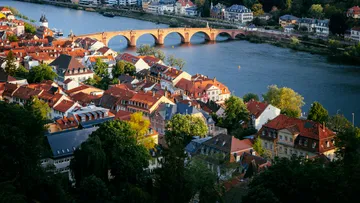Old bridge over river with cityscape.
