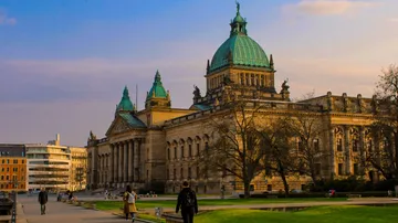 Personen gehen nahe großes historisches Gebäude.