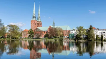 Kirche mit Doppeltürmen spiegelt sich im See.