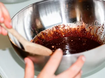 Bowl contains chocolate mixture, is stirred with a spoon.