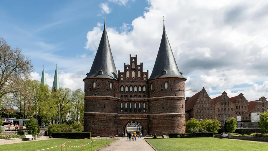 Historic brick gate with two towers in a park.
