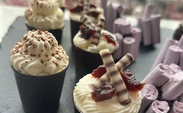 Schokoladendesserts mit Sahne auf schwarzem Tablett.