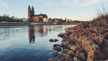 Cathedral reflected in river, surrounded by rocks.