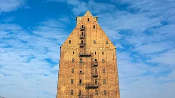 Tall brick building, metal stairs, blue sky.