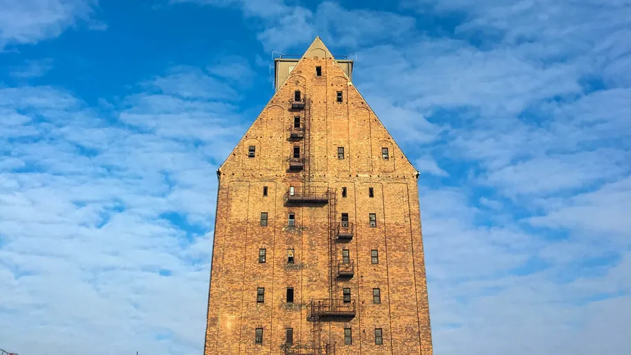 Tall brick building, metal stairs, blue sky.