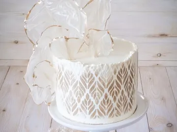Kuchen mit eleganter, blütenähnlicher Dekoration auf einer Platte.