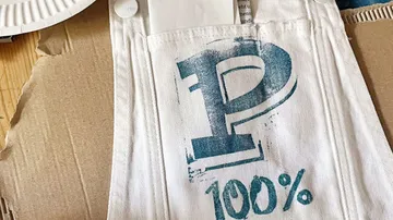 Weißer Stoff mit großem 'P' und '100%'.