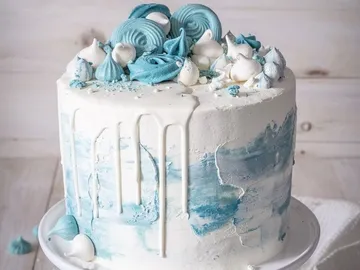 Torte mit blauer Dekoration und Zuckerguss, auf einem Teller.