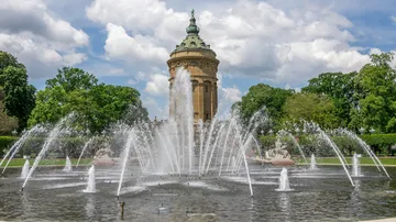 Springbrunnen sprüht Wasser vor Wasserturm.