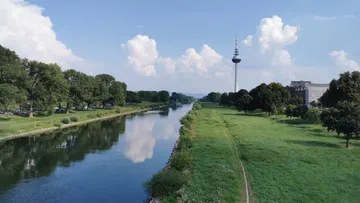 Riverside scene with tower and trees.