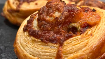 Gebäck mit Tomate, Käse und Olivenbelag.