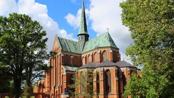 Gotische Kirche mit hohem Turm und Bäumen.