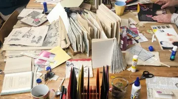 Craft table with papers, scissors, glue, books.