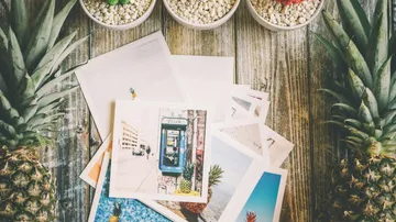 Postcards with pineapples on rustic table.