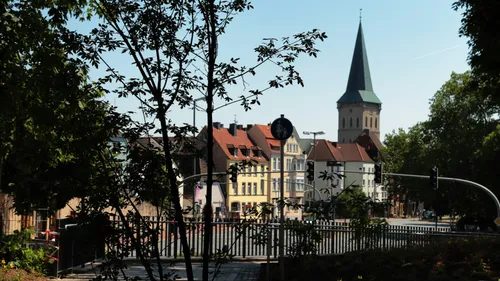 Baum rahmt Blick auf Kirche und Gebäude.
