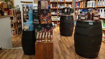 Whiskeyladen-Innenraum mit Fässern und Flaschen.