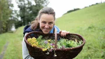 Person holding a basket of herbs outdoors.