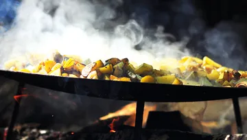 Potatoes cooking in a pan over fire.