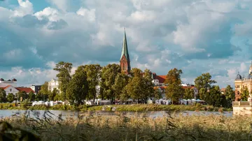 Church surrounded by trees near a lake.