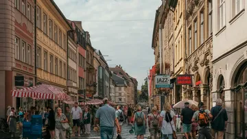 Menschen laufen auf belebter Stadtstraße.