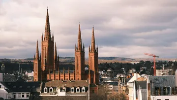 Red-brick church with tall spires, urban background.