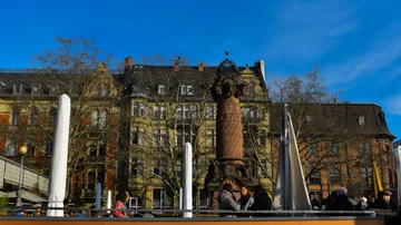 Historic lamppost in urban outdoor cafe setting.