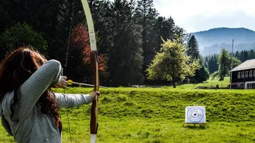 Bogenschütze zielt auf Ziel im Grasfeld.