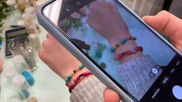 Person fotografiert Handgelenk mit bunten Armbändern.