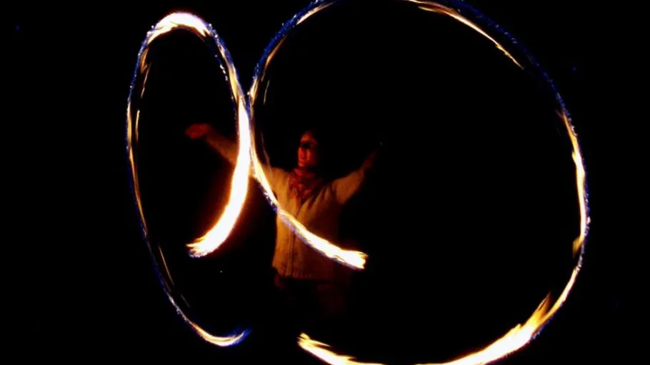 Person spinning fire poi at night.