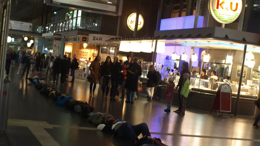 Menschen liegen auf Boden in geschäftigem Innenmarkt.