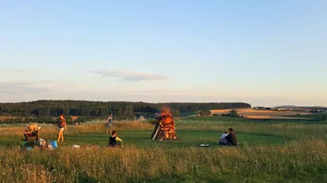 People gathered around bonfire in field.