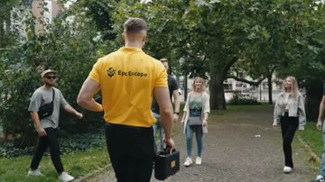 Mann im gelben Hemd geht auf Gruppe zu draußen.