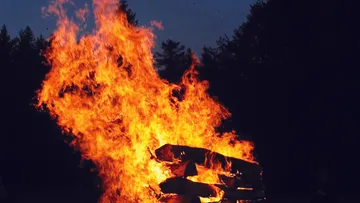 Großes Lagerfeuer brennt im dunklen Wald.