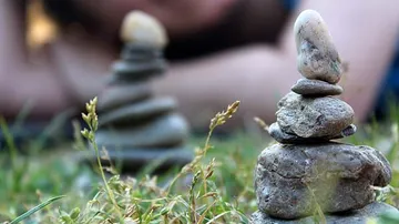 Kleine gestapelte Steine auf Gras mit unscharfem Hintergrund.