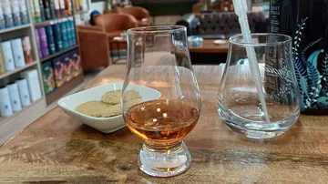 Whiskeyglas auf Tisch mit Keksen in der Nähe.