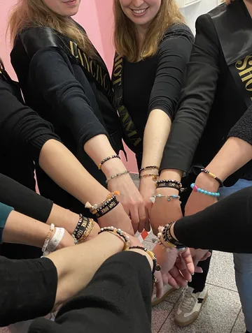 Frauen mit Schärpen und Armbändern, Hände zusammen.