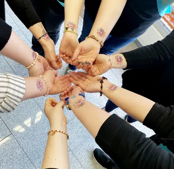 Hands with tattoos form a circle indoors.