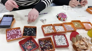 People crafting with beads at a table.
