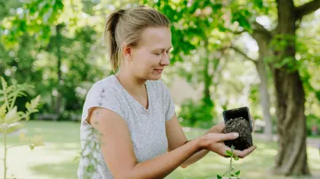 Woman holding plant in garden.
