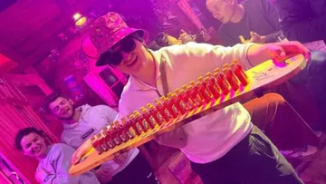 Person holding tray with shots at party.