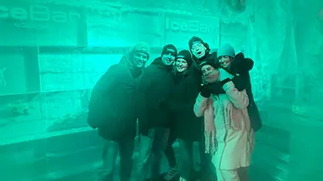 Group posing inside ice bar with blue lighting.