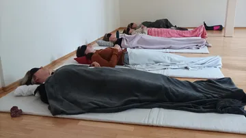 Women lying under blankets in a yoga studio.