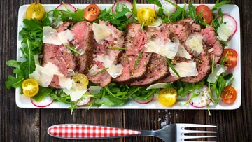 Geschnittenes Rindfleisch auf Rucola mit Kirschtomaten.