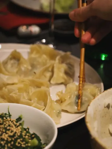 Hand using chopsticks to pick dumplings.