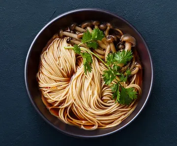 Noodles and mushrooms in a dark bowl.