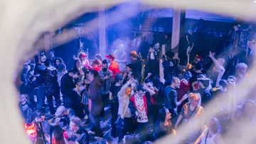 Menschen in Kostümen tanzen auf einer Party.