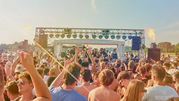Crowd enjoying outdoor music festival in daylight.